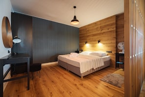 A modern bedroom with a bed, bedside tables, a desk, and a chair.
