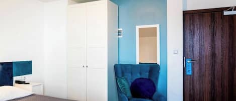 A bedroom with a bed, a wardrobe, a chair, and a door.