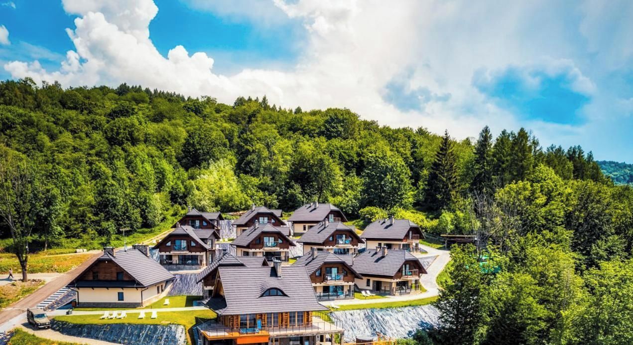 A cluster of chalet-style buildings with sloped roofs, surrounded by dense forest.