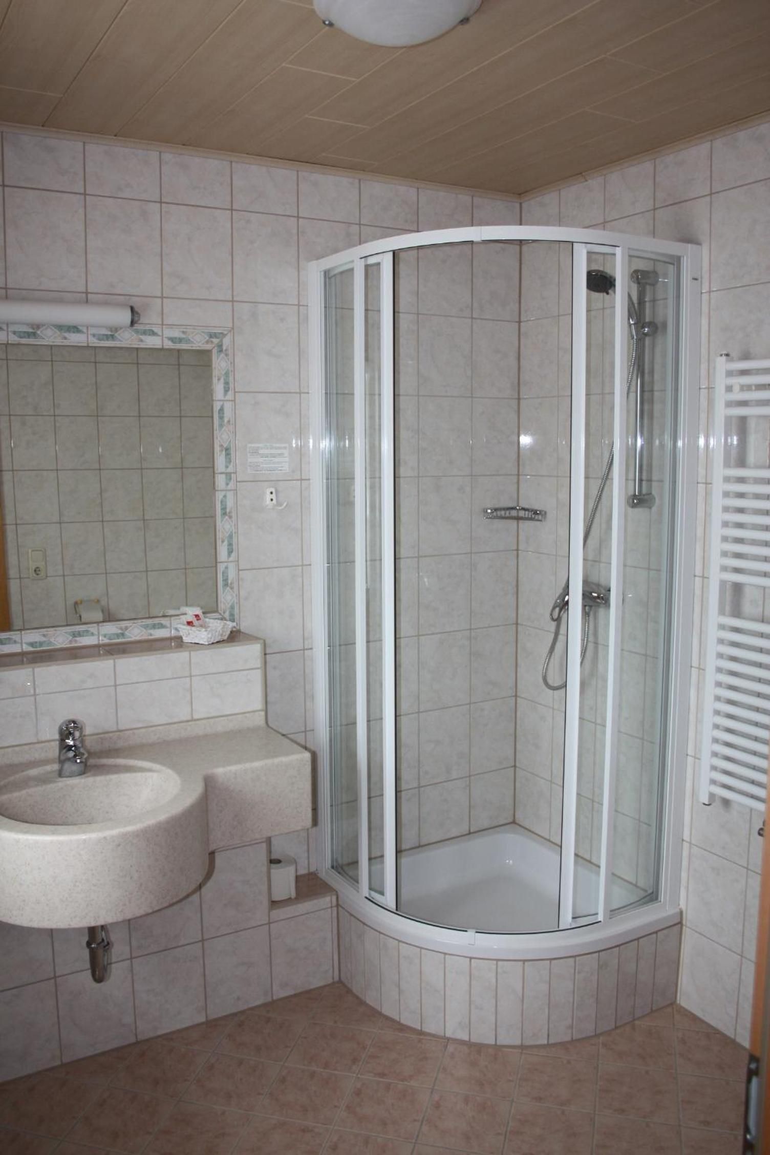 Ein Badezimmer mit einer Duschkabine, einem Waschbecken und einem Spiegel.