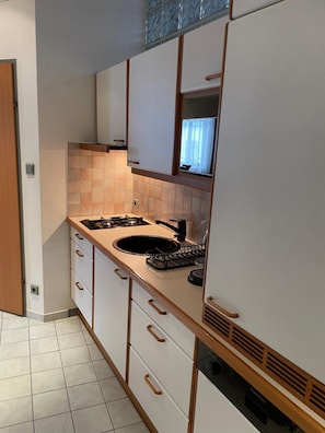 Cocina pequeña con lavamanos, estufa y armarios de madera.