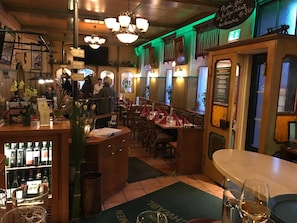 Un interior de restaurante con mobiliario de madera, una zona de bar y un panel con la carta.