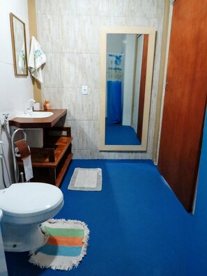 A bathroom with a toilet, sink, and mirror.