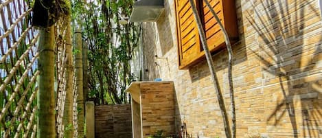 A narrow pathway leading to a building with a wooden door and window shutters.
