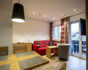 Una sala de estar moderna con un sofá rojo, una mesa de comedor de madera y un sillón gris.