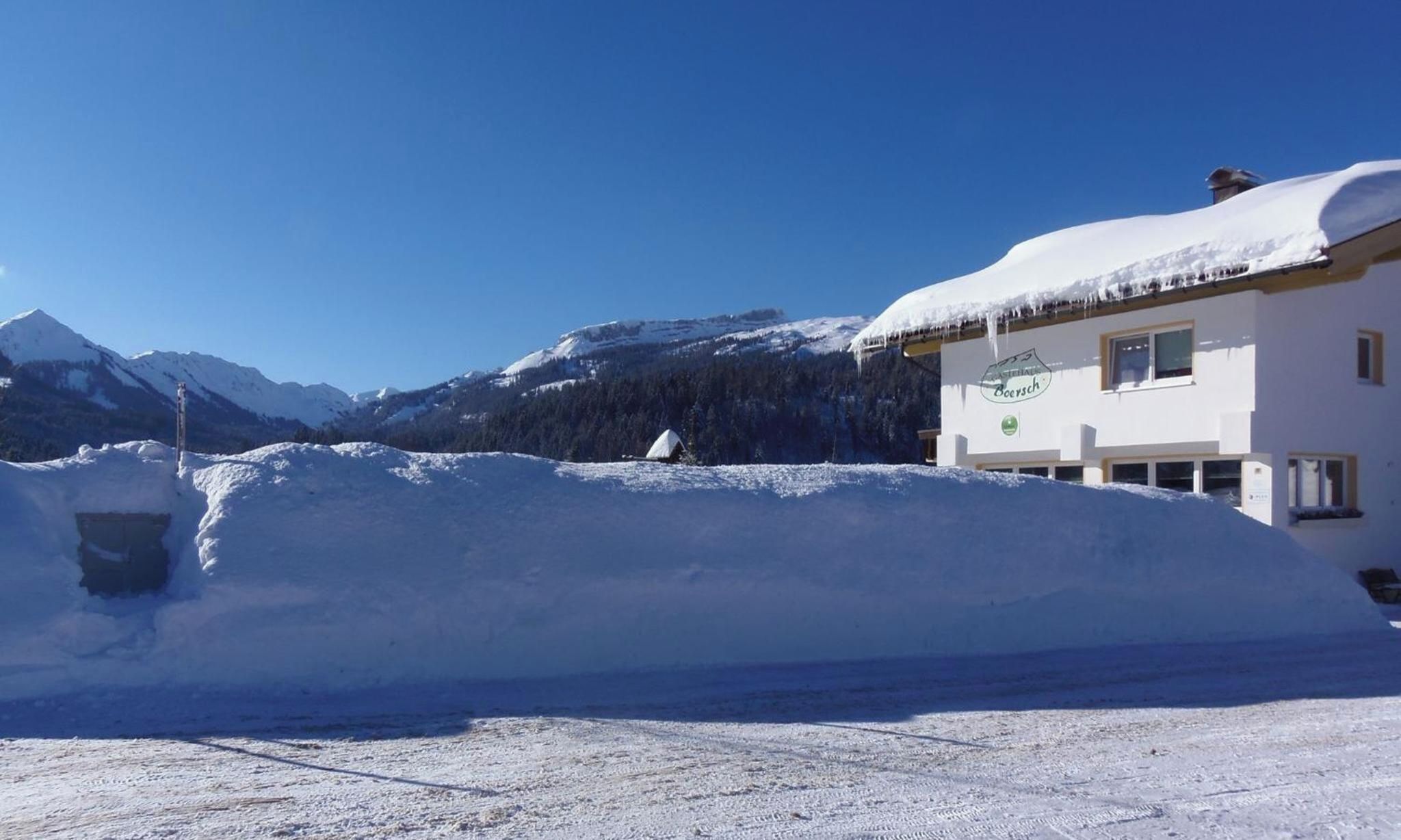 Un bâtiment recouvert de neige, avec un ciel dégagé et des montagnes en arrière-plan.