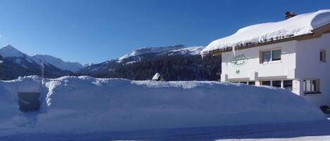 Un bâtiment recouvert de neige, avec un ciel dégagé et des montagnes en arrière-plan.
