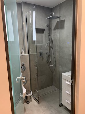 A modern bathroom with a glass-enclosed shower, a toilet, and a vanity with drawers. - Haus 7 - Boardinghouse (Kornwestheim)