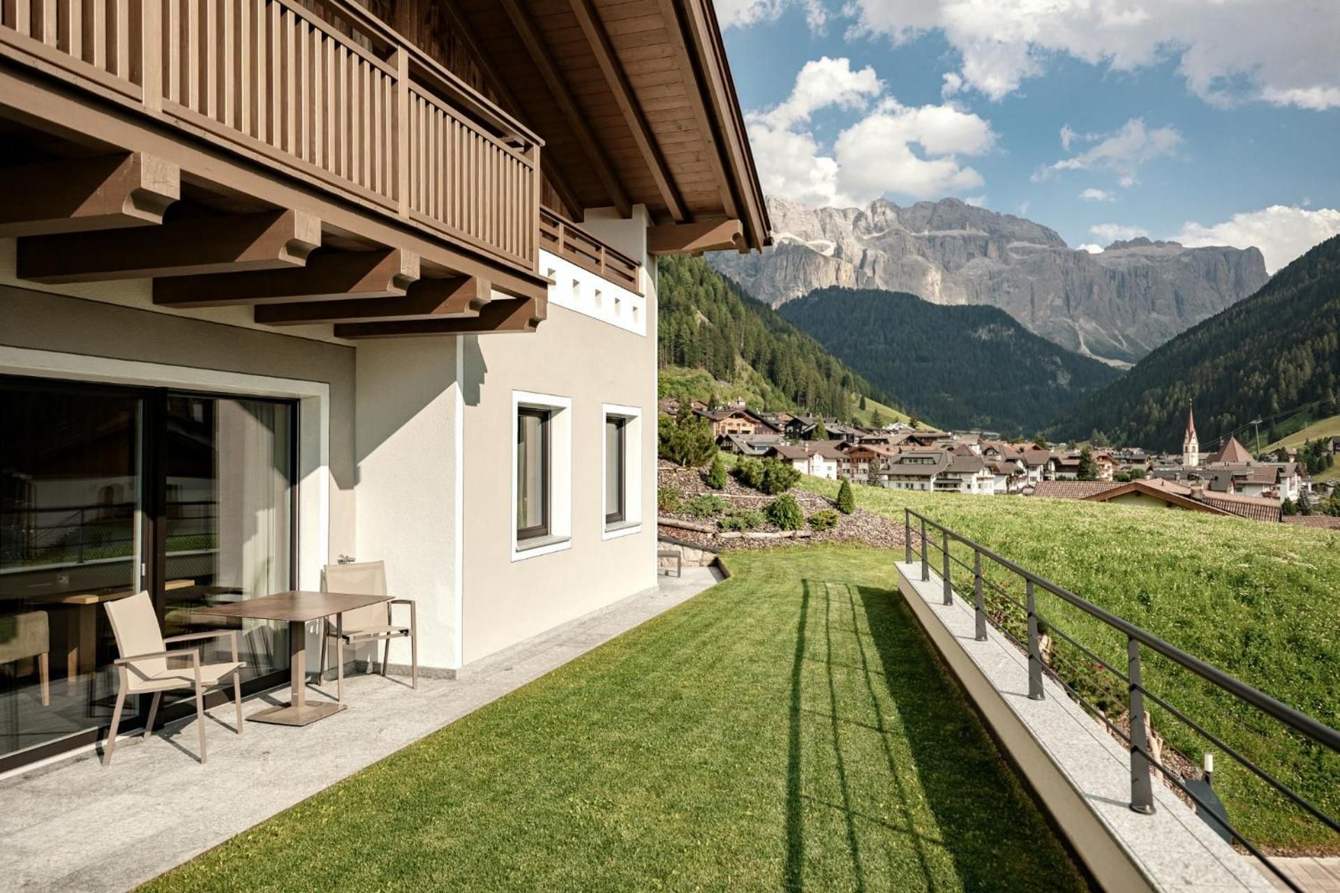 A modern building with a balcony overlooking a mountain village and a clear sky.