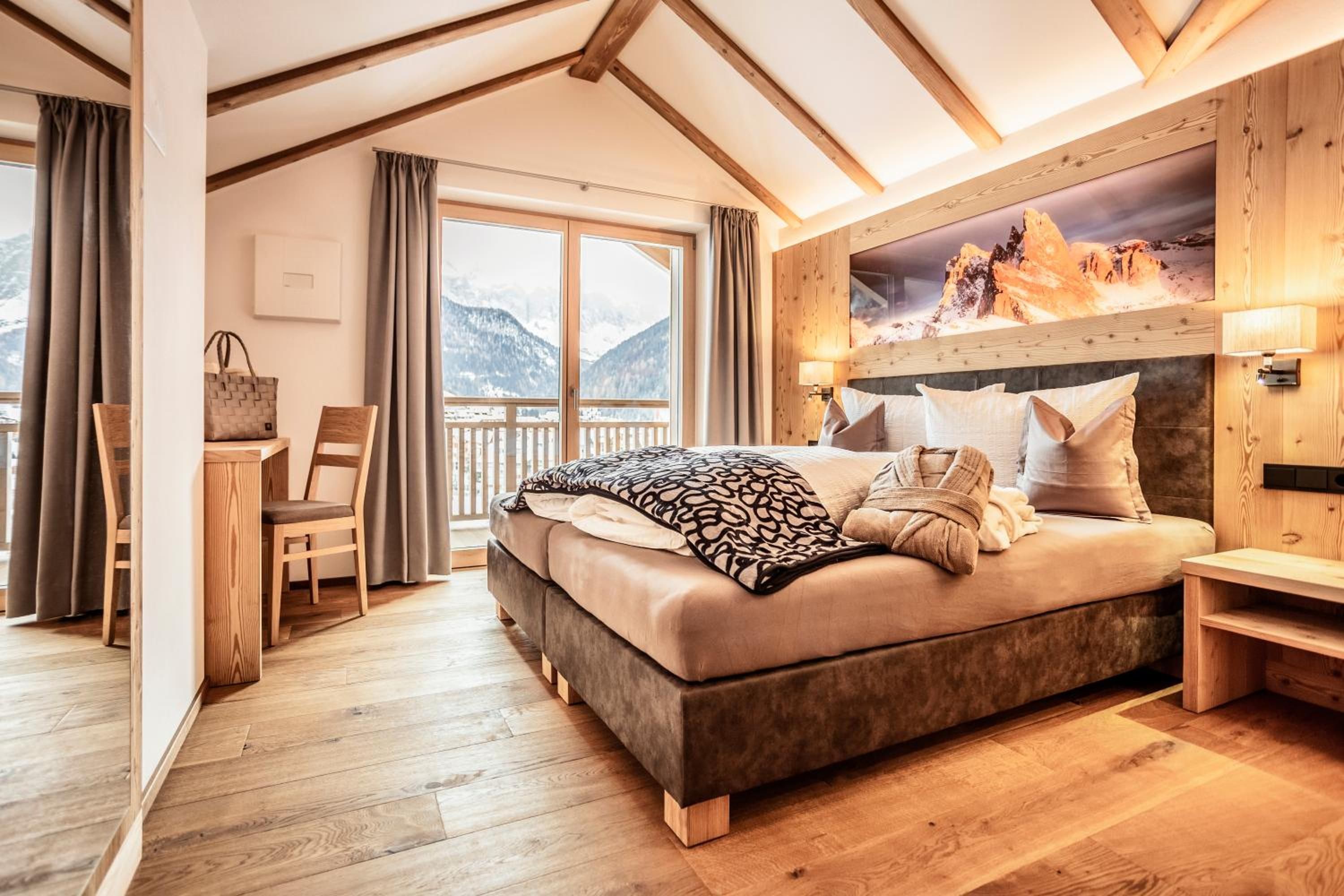 Un dormitorio con una cama grande, piso de madera, un escritorio y una silla.