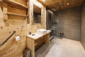 Un baño de madera con lavamanos, espejo y ducha.