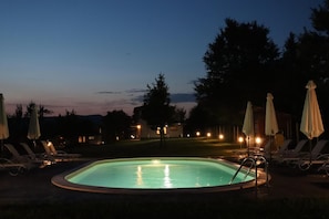 A swimming pool with lounge chairs and umbrellas, surrounded by trees and houses. - Sinjirite Complex (Elena)