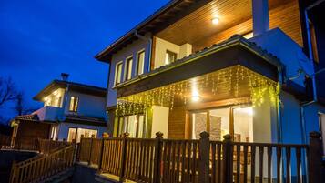 A two-story house with a wooden deck and string lights.
