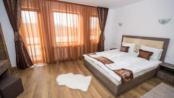 A hotel room with a large bed, wooden flooring, and curtains.