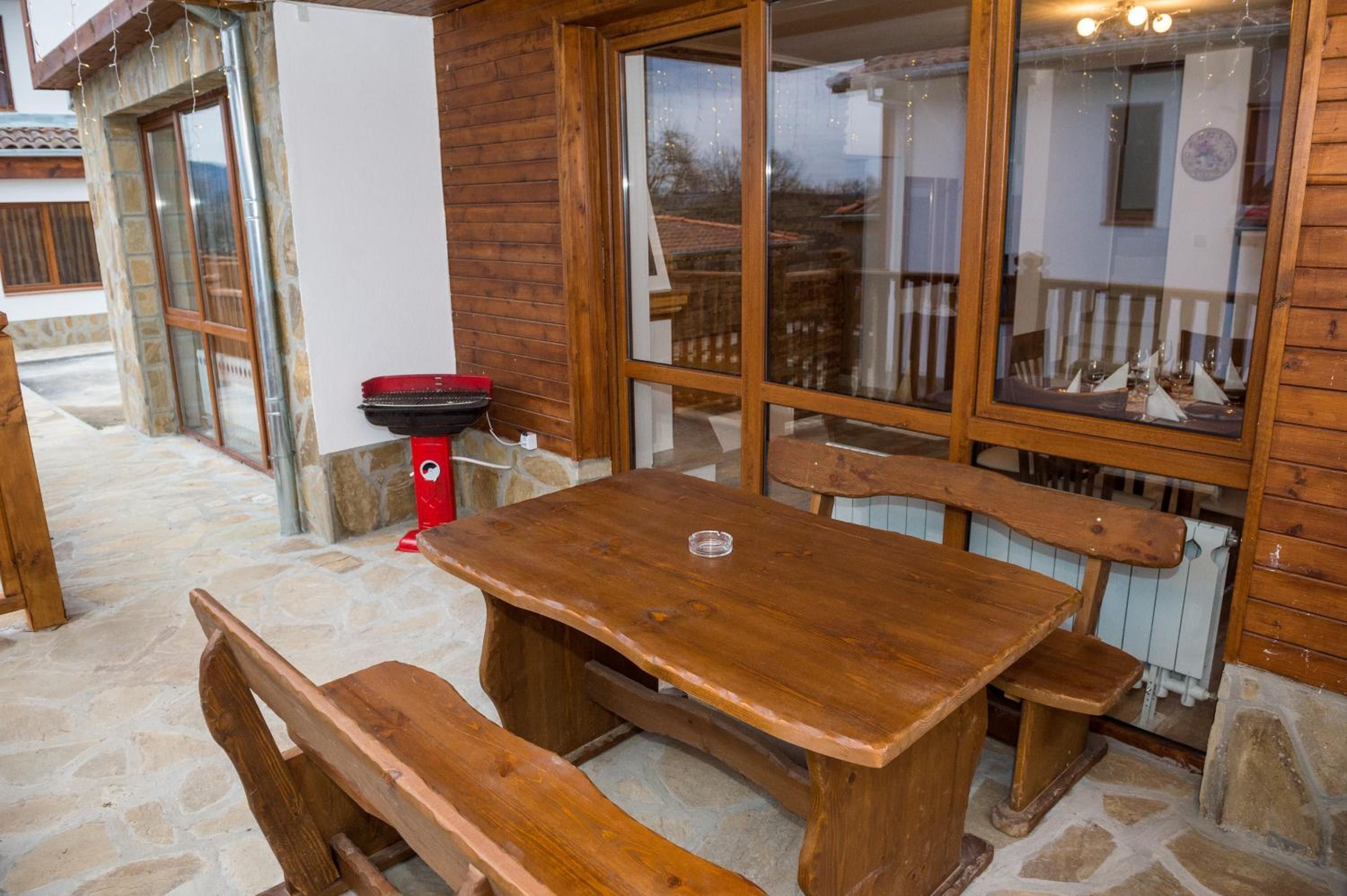 A wooden table and benches in an outdoor setting with stone flooring.