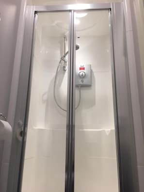 Box de chuveiro envidraçado com painel de controle e chuveiro manual.