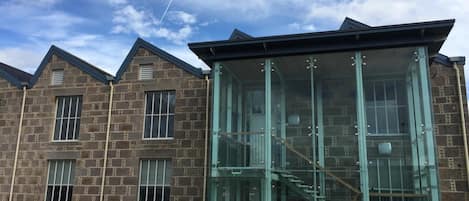 A stone building with a glass elevator shaft and a staircase.