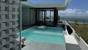 A modern infinity pool with a clear view of the ocean, a glass-enclosed spa area, and a seating area with a view. - Pousada Mestizo (Touros)