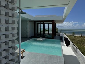 A modern infinity pool with a clear view of the ocean, a glass-enclosed spa area, and a seating area with a view. - Pousada Mestizo (Touros)
