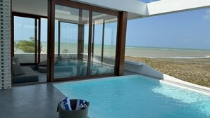 A modern infinity pool with a clear view of the beach, a seating area with cushions, and a wicker basket. - Pousada Mestizo (Touros)