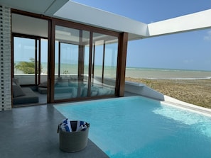 A modern infinity pool with a clear view of the beach, a seating area with cushions, and a wicker basket. - Pousada Mestizo (Touros)