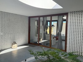 Un interior moderno con un amplio ventanal que da a un espacio exterior, una pared con diseño y una planta pequeña.