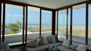 A modern interior with a large window overlooking a beach. - Pousada Mestizo (Touros)