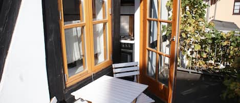 A small outdoor seating area with a table and chairs, a wooden door, and a window.