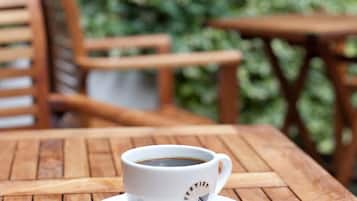 Eine weiße Kaffeetasse mit Löffel auf einem Holztisch im Freien.