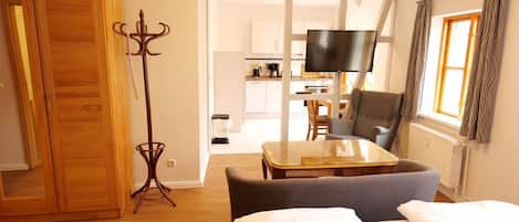 A hotel room with a bed, a television, a dining table, and a chair.