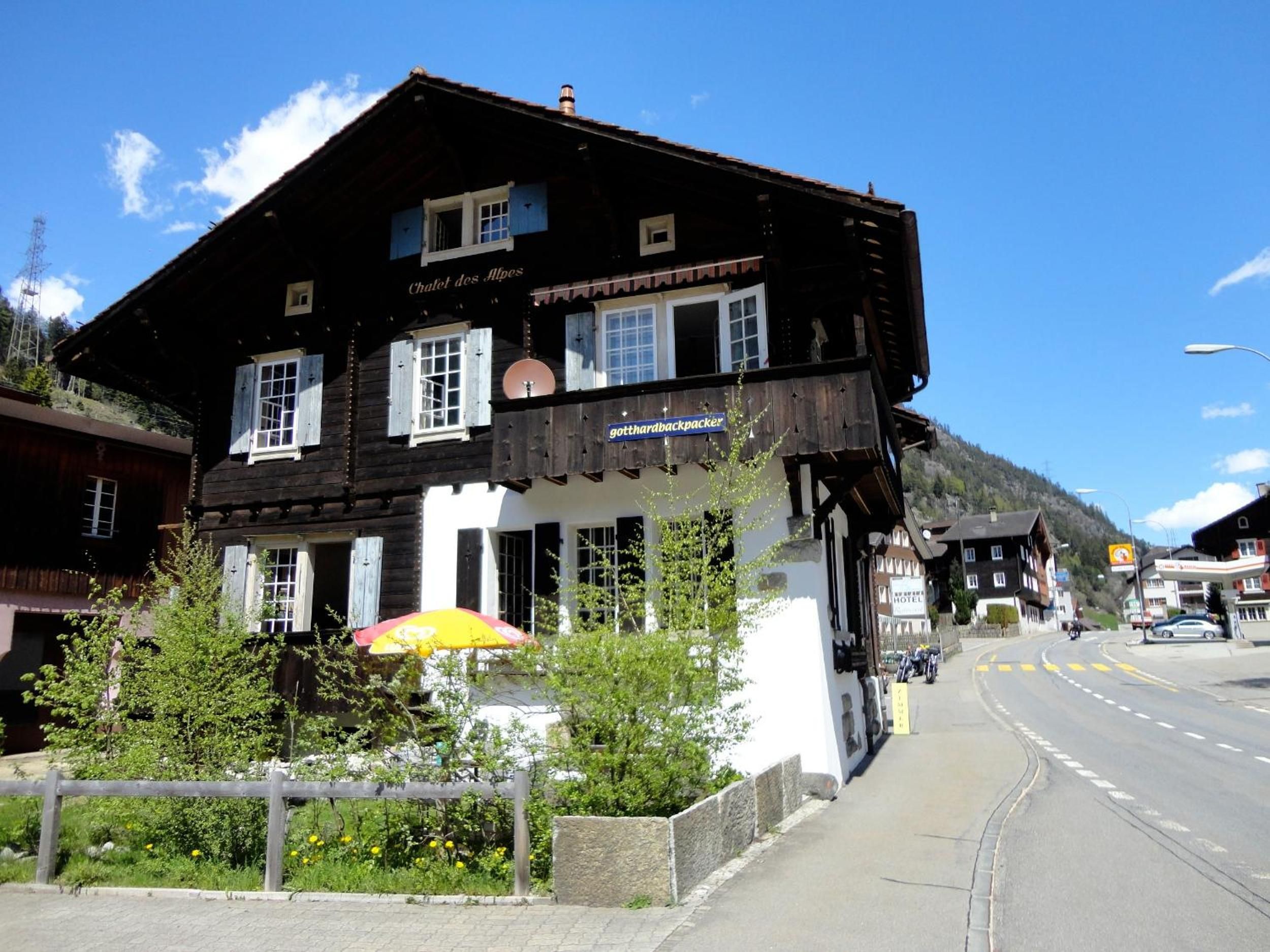 Un bâtiment de style chalet traditionnel, avec une enseigne indiquant « Chalet des Alpes » et une autre indiquant « gotthard backpacker ».