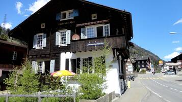 Un bâtiment de style chalet traditionnel, avec une enseigne indiquant « Chalet des Alpes » et une autre indiquant « gotthard backpacker ».