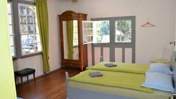 Une pièce comprenant un lit, un banc, un miroir et une fenêtre avec des rideaux.