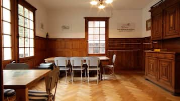 Une cuisine spacieuse avec un plancher en bois, une table à manger avec des chaises, un lustre et des armoires en bois.