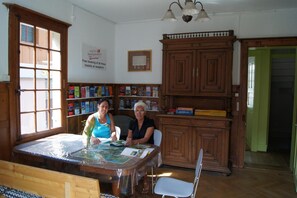 A room with a wooden cabinet, a table with a map, and a sign advertising free booking for Swiss backpackers. - Gotthard Backpacker (Wassen)