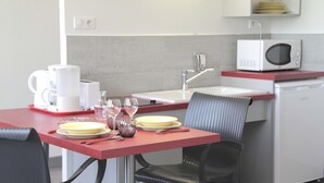 A compact kitchenette with a microwave, sink, and a small refrigerator. - West Appart' Hôtel (Bessines)