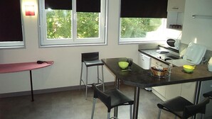 A compact kitchen with a dining area, including a table, chairs, and a microwave. - West Appart' Hôtel (Bessines)