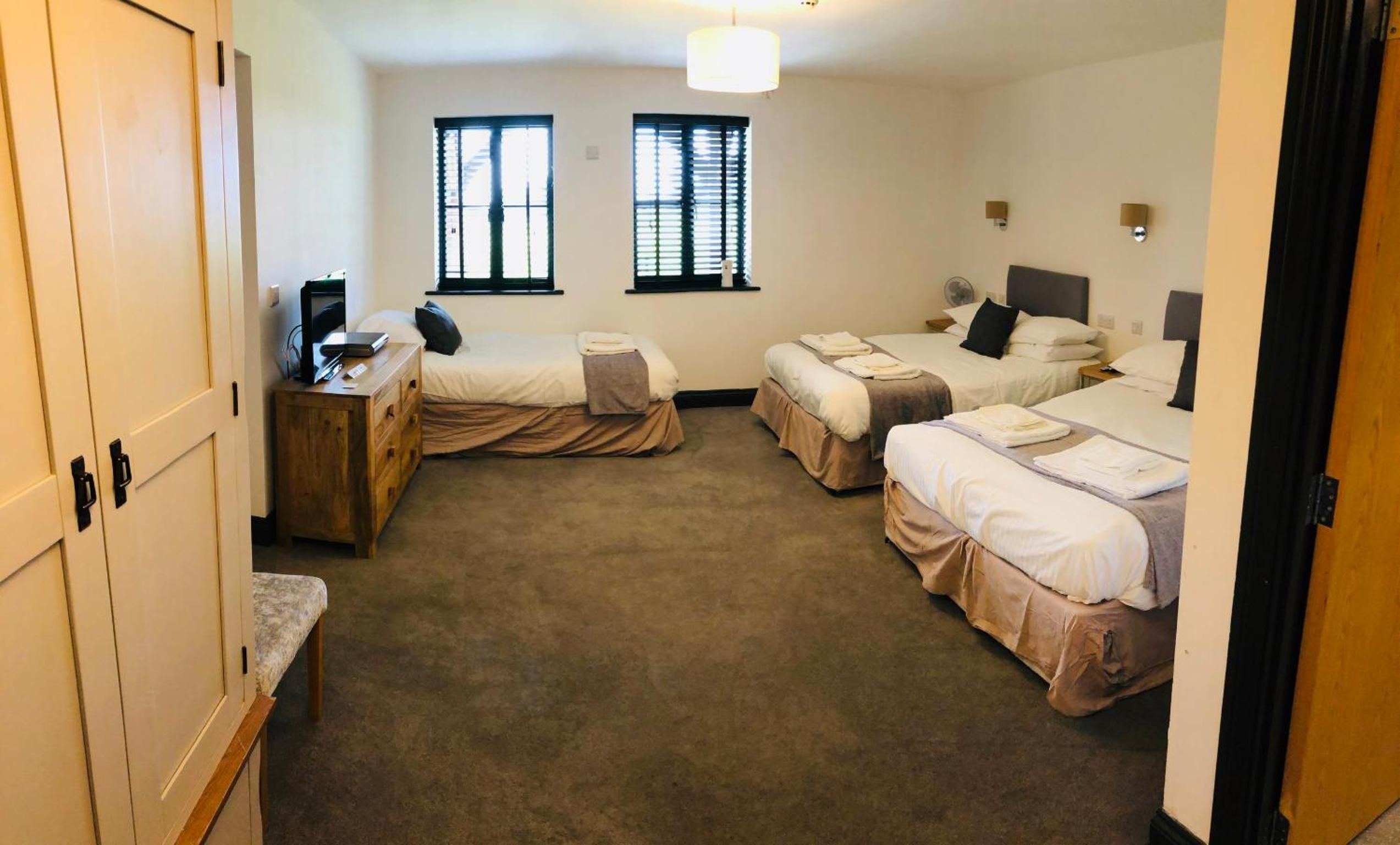 A hotel room with three beds, a desk, and a wardrobe.