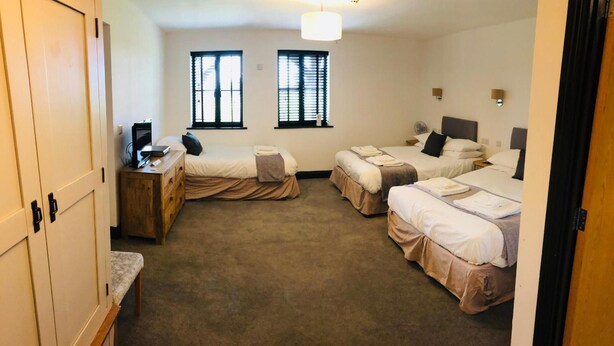 A hotel room with three beds, a desk, and a wardrobe. - The Players Golf Club (Bristol)