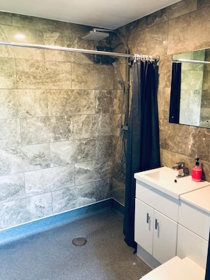 A bathroom with a shower, a sink with a mirror, and a toilet. - The Players Golf Club (Bristol)