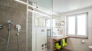 Un baño moderno con cabina de ducha de vidrio, un lavabo y un espejo.