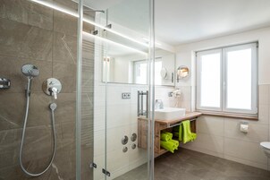 A modern bathroom with a glass shower enclosure, a sink, and a mirror.