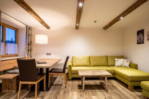 Una sala acogedora con una mesa de comedor de madera, un sofá verde y una pequeña mesa de centro de madera.