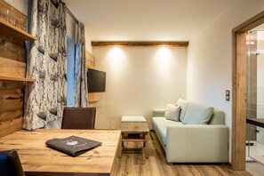 Una sala de estar moderna con un sofá, una mesa de centro, un televisor montado en la pared y un estante de madera.