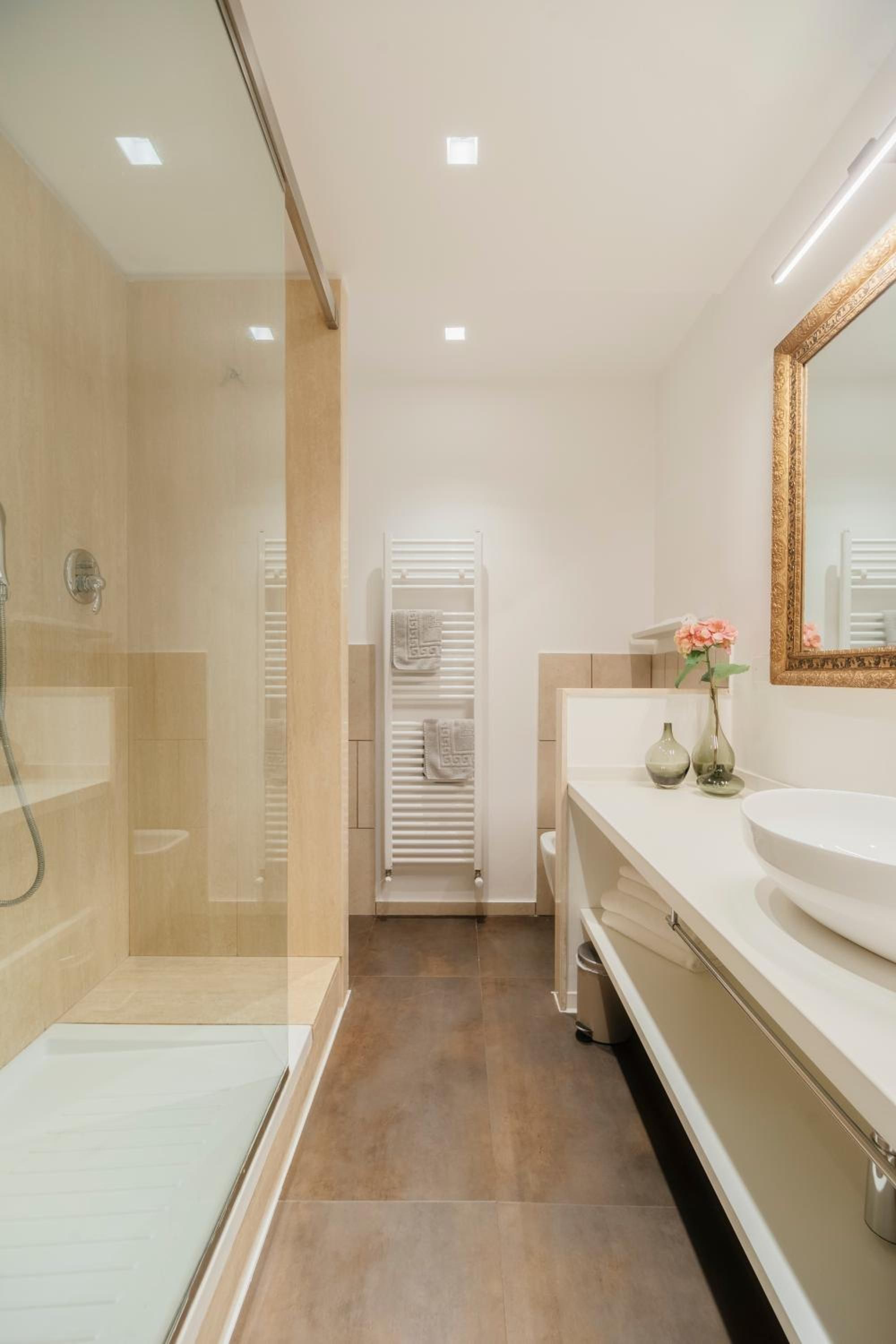 Ein modernes Badezimmer mit einer Duschkabine aus Glas, einem weißen Waschbecken und einem großen Spiegel.