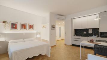 Una camera d'albergo moderna con un letto, un tavolino e angolo cottura.
