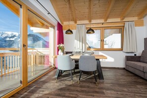 Un comedor con una mesa de madera, dos sillas y vistas a una montaña nevada.