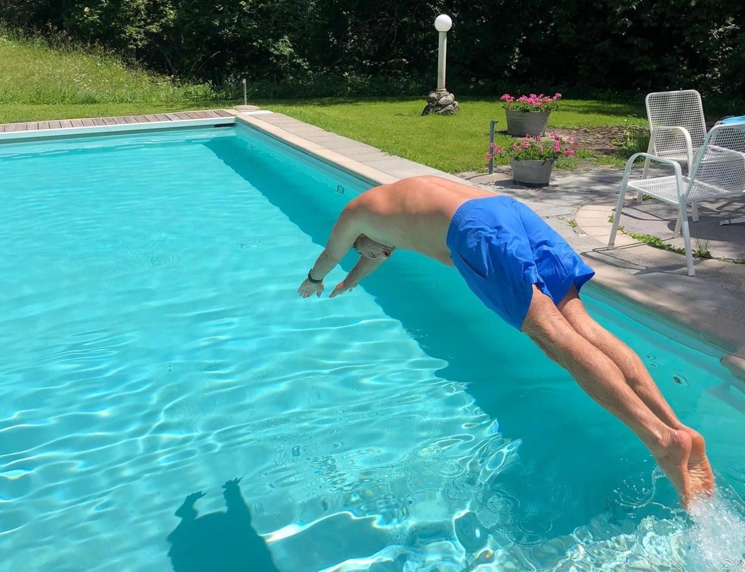 Une piscine à l’eau d’un bleu limpide, entourée d’une pelouse et agrémentée de quelques plantes en pot.