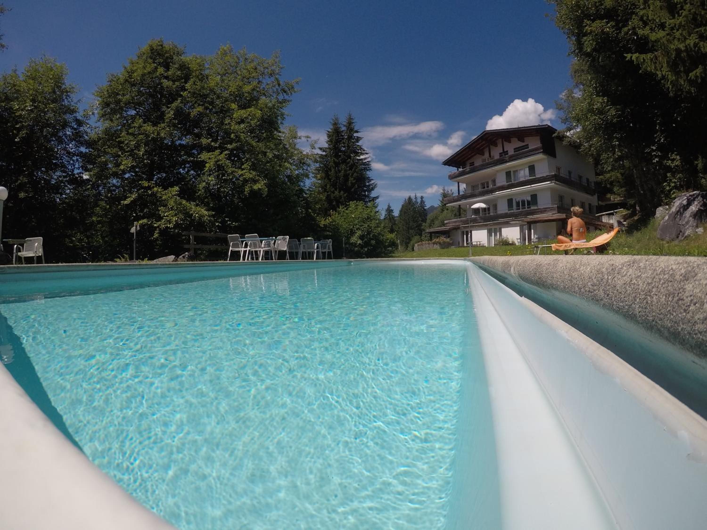 Une piscine aux eaux cristallines, avec des chaises longues et un bâtiment en arrière-plan.