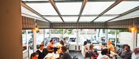 Un restaurante con techo de vidrio, mesas y sillas dispuestas para comer.